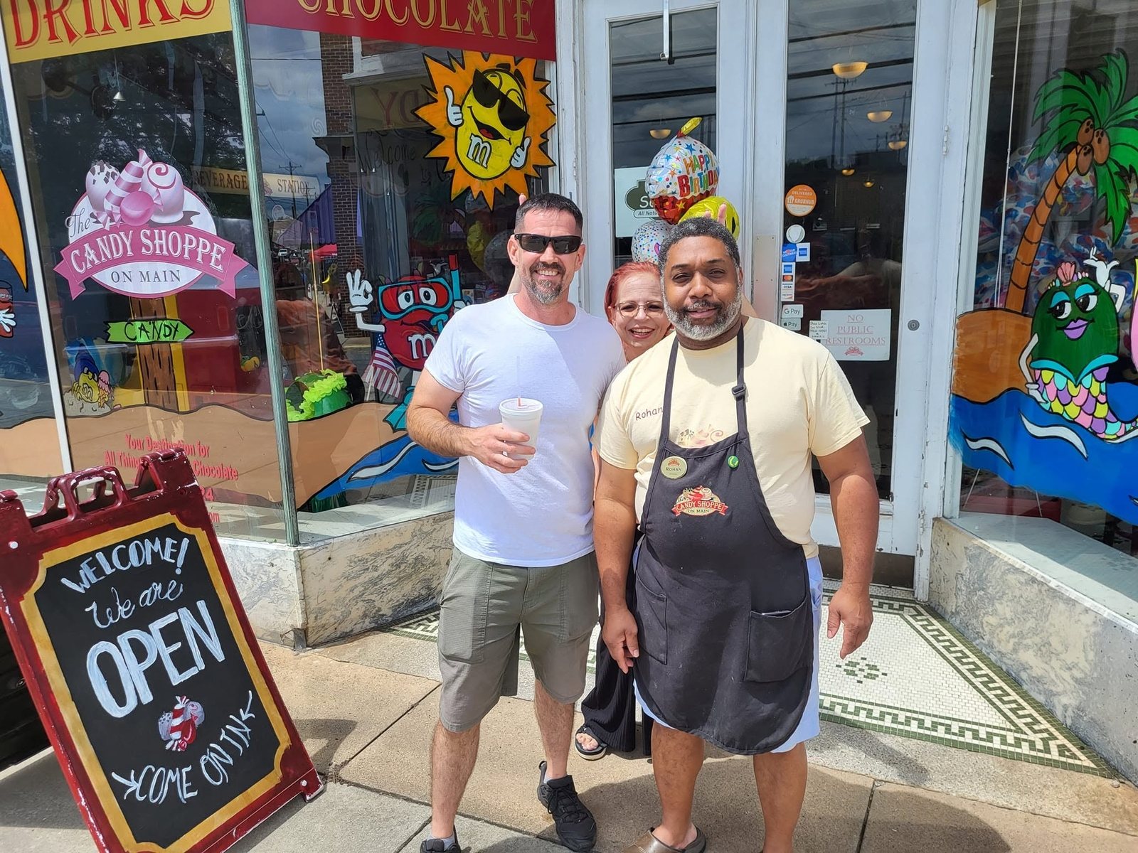 Owner Rohan Banton with customers outside The Candy Shoppe on Main