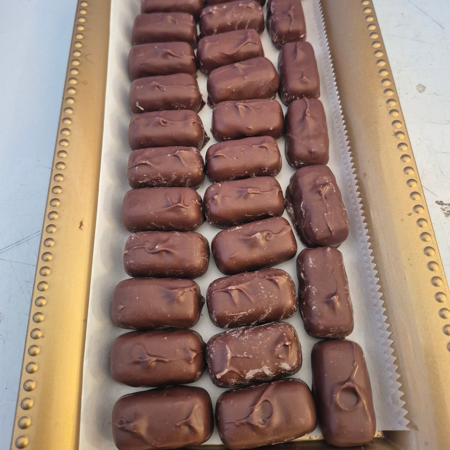 Chocolate-covered caramels lined up on a tray at The Candy Shoppe on Main